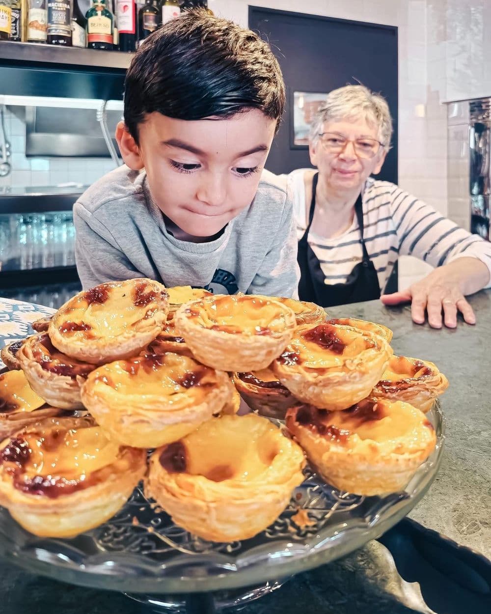 Le petit-fils de la famille Ferraria devant un plateau de pastéis de nata, restaurant João's à Toulon