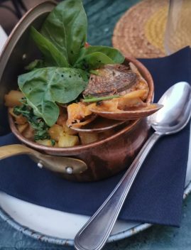 Plat de fruits de mer portugais dans un récipient en terre cuite, garni de verdure fraîche et servie avec une cuillère